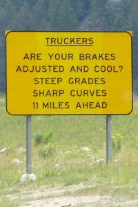 A highway sign warning truckers to check their brakes before starting down a steep grade.